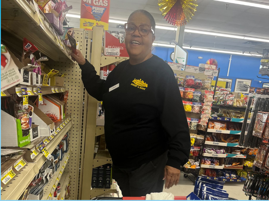 Woman stocking shelves while smiling for the camera